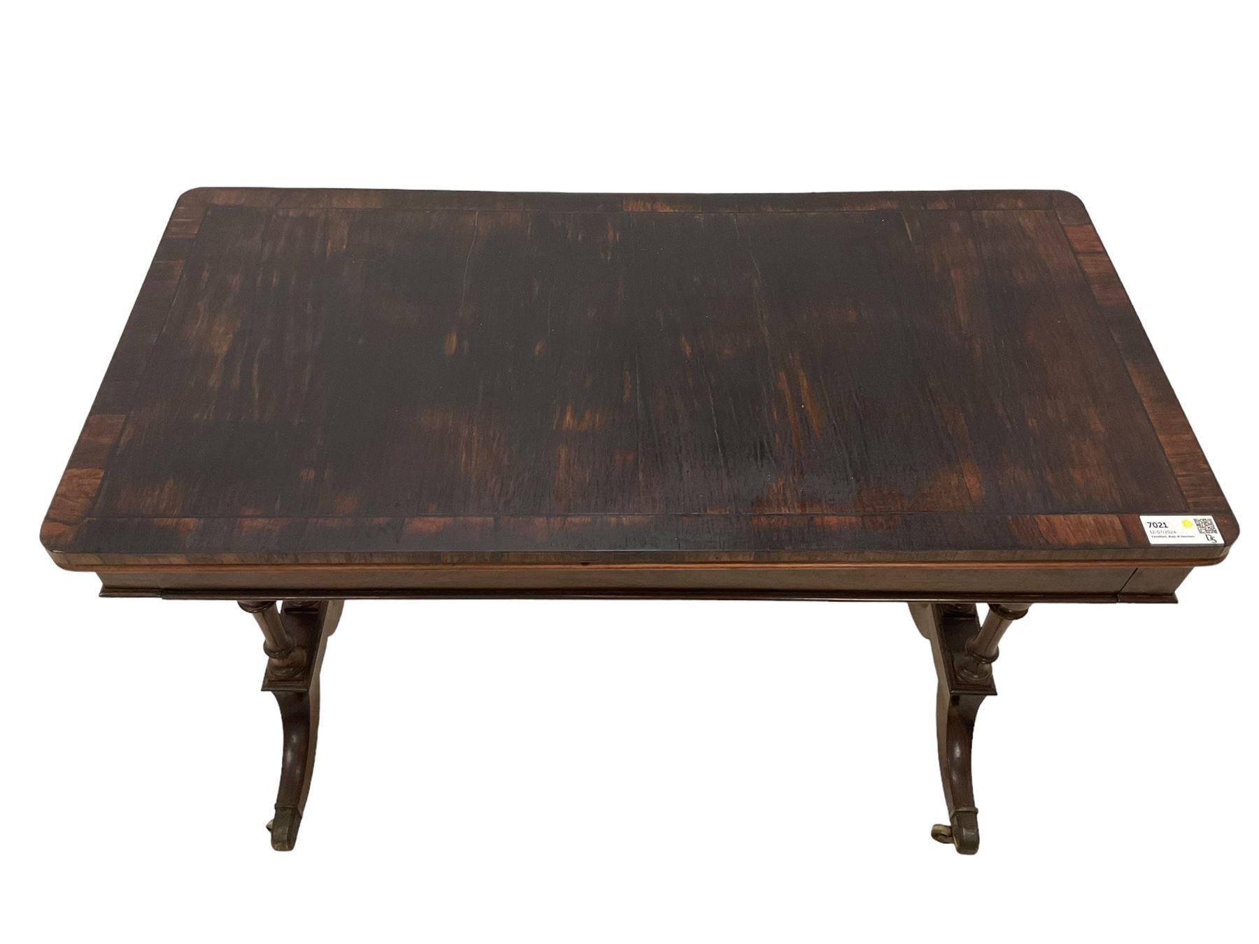 Regency rosewood card table, fold-over swivel action rectangular top with crossbanding, single frieze drawer, raised on turned end supports terminating in splayed feet with castors, joined by ring turned stretcher