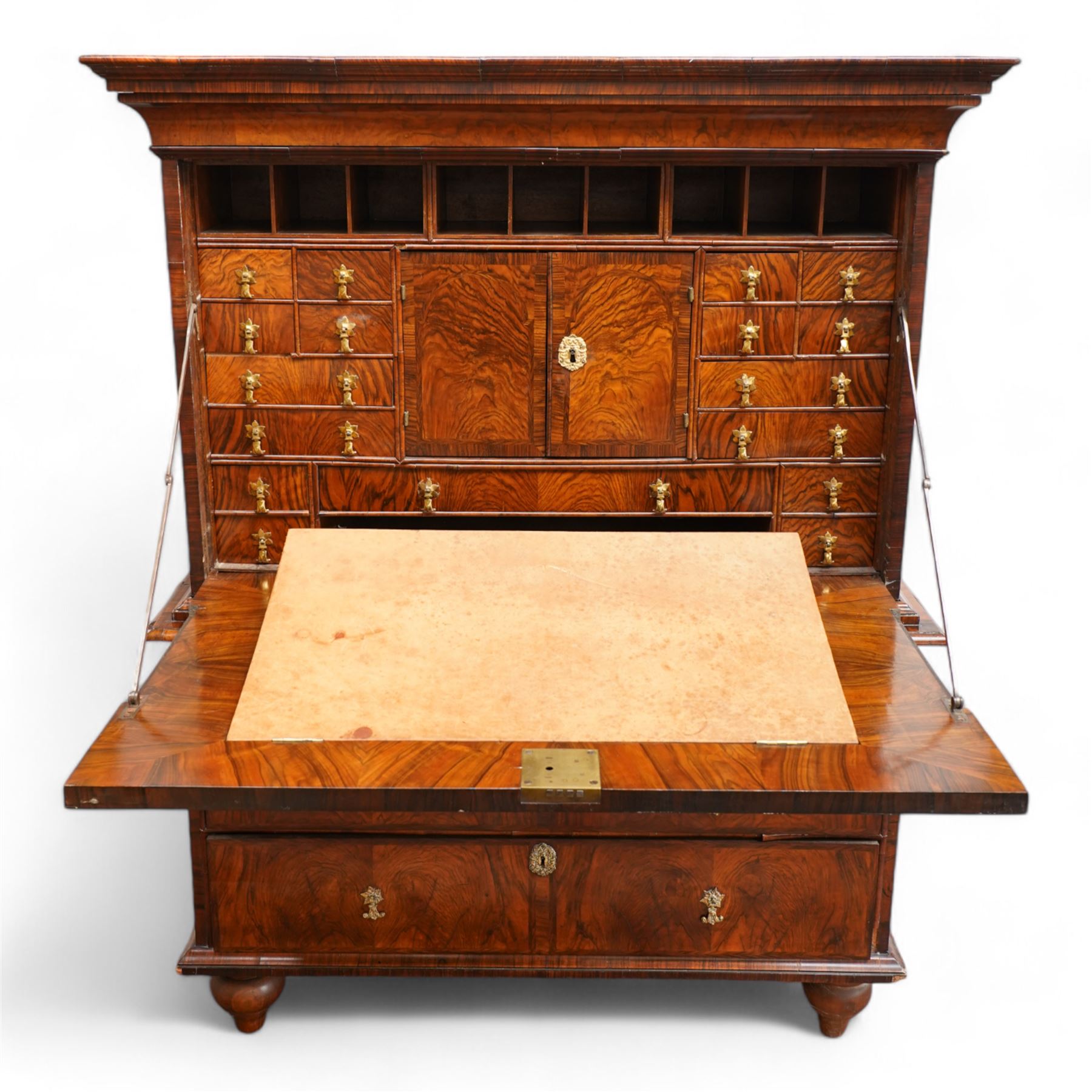 George II figured walnut escritoire, projecting moulded cornice over cavetto frieze with drawer, figured fall front revealing pigeonholes, a combination of drawers, central double cupboard and hidden drawers, fitted with two short and two long drawers, cast gilt metal escutcheons and drop handles, on turned feet 