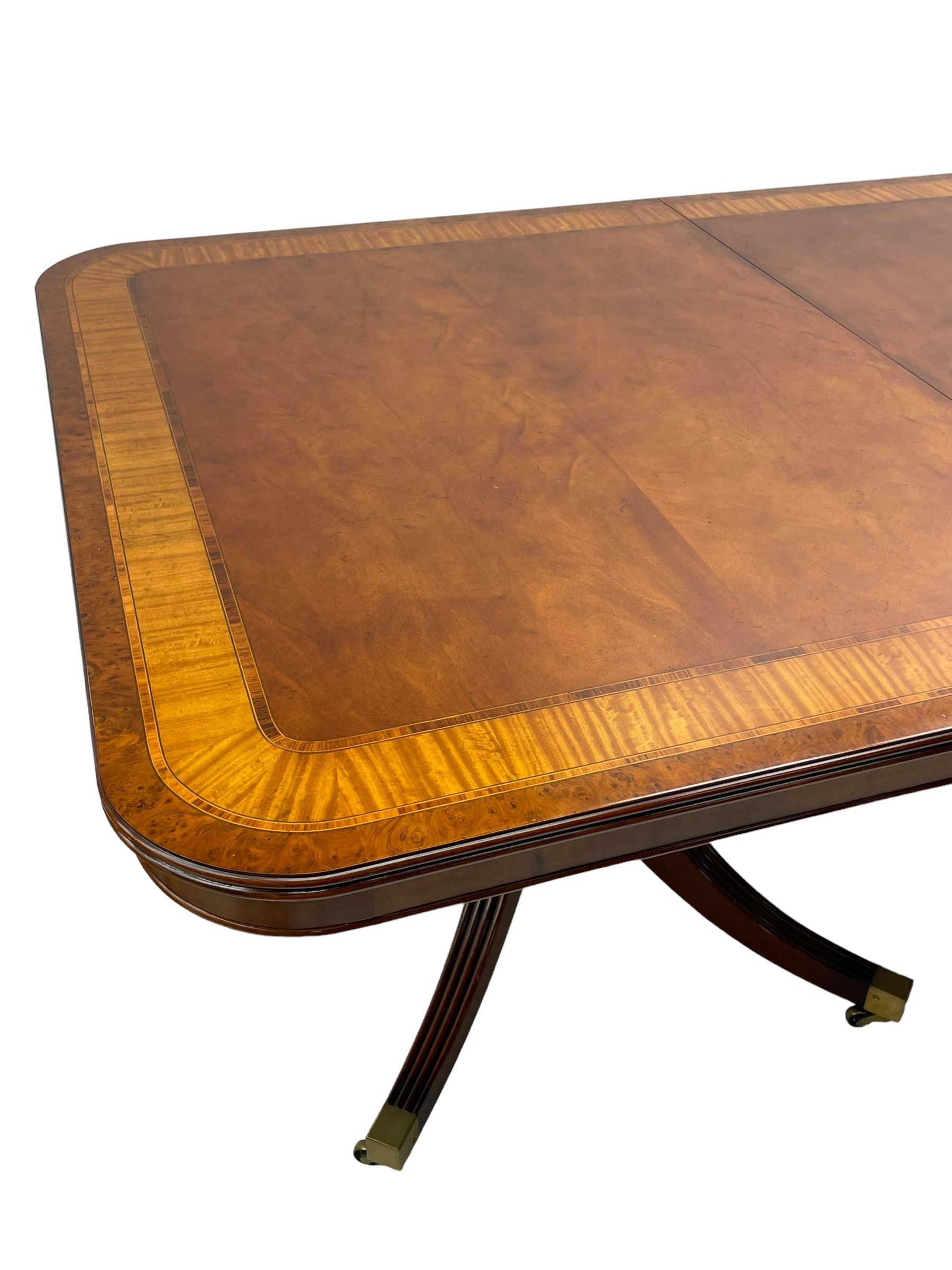 RBC Furniture (Made in England) - Georgian design mahogany dining table, rectangular top with rounded corners, satinwood and burr walnut bandings, two D-ends with two additional leaves and support rails, on barrel turned pedestals with four out-splayed reeded supports, brass cups and castors 