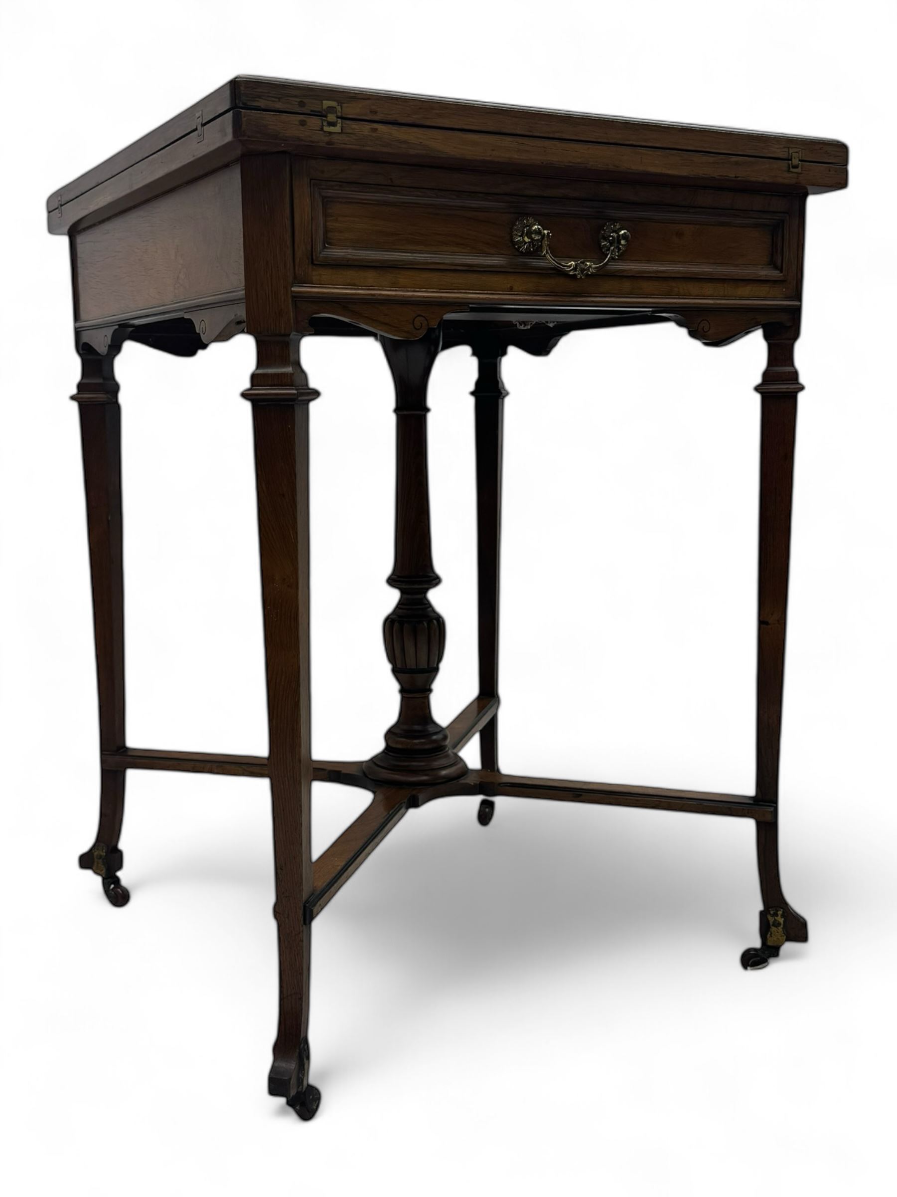 Victorian rosewood envelope games table, the moulded square top with four triangular hinged leaves, revealing inset baize playing surface and sunken counter wells, fitted with single frieze drawer, on square tapering supports united by x-framed stretchers and turned central column, on brass and ceramic castors 