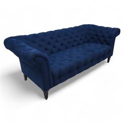 Chesterfield three-seat sofa, traditional shape with rolled arms, upholstered in deep blue buttoned fabric, on black finish turned front feet 