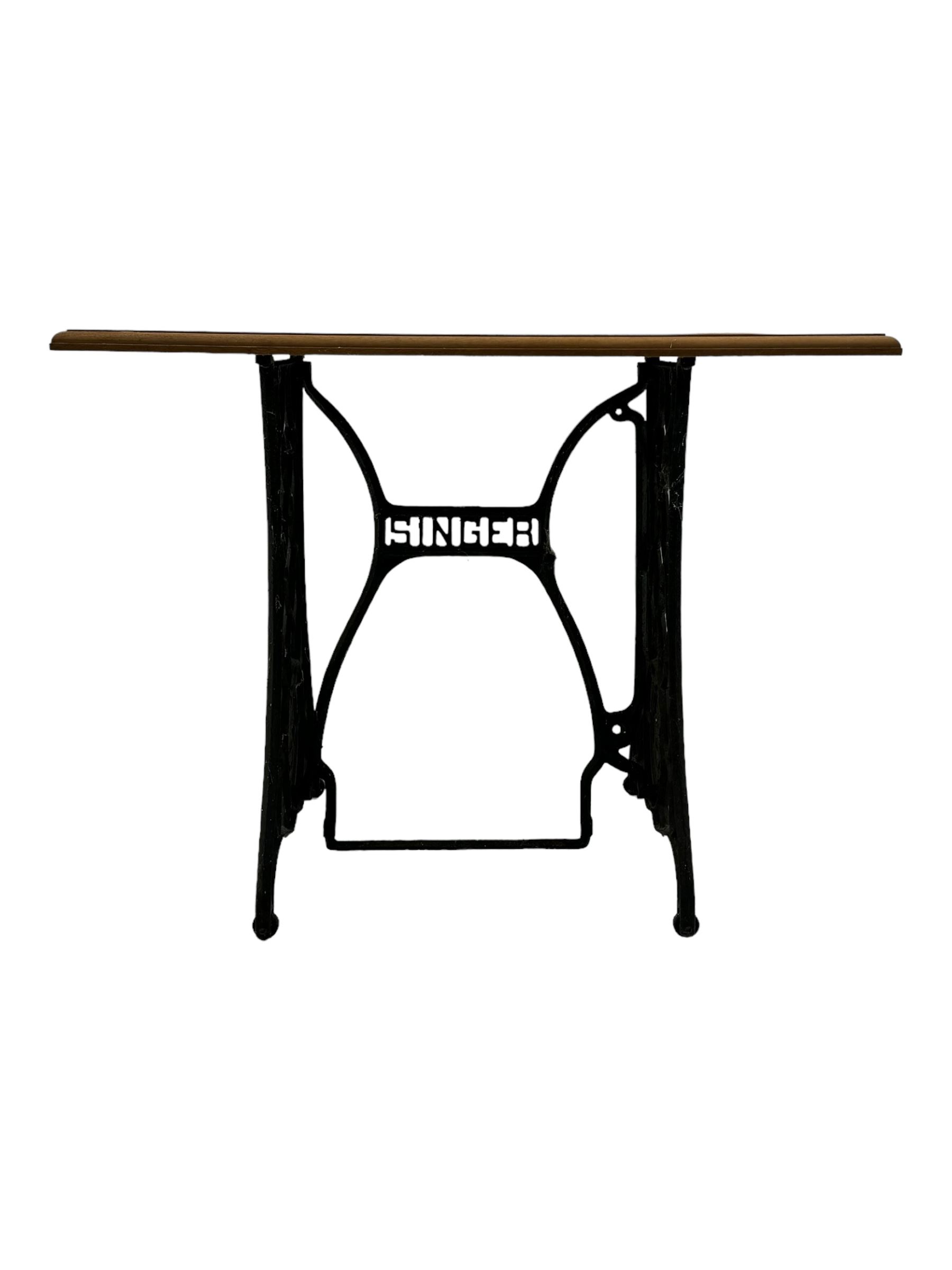 Late 19th century Singer sewing table, rectangular mahogany top mounted on a black cast iron base with decorative scrollwork and 'Singer' logo, on curved supports 