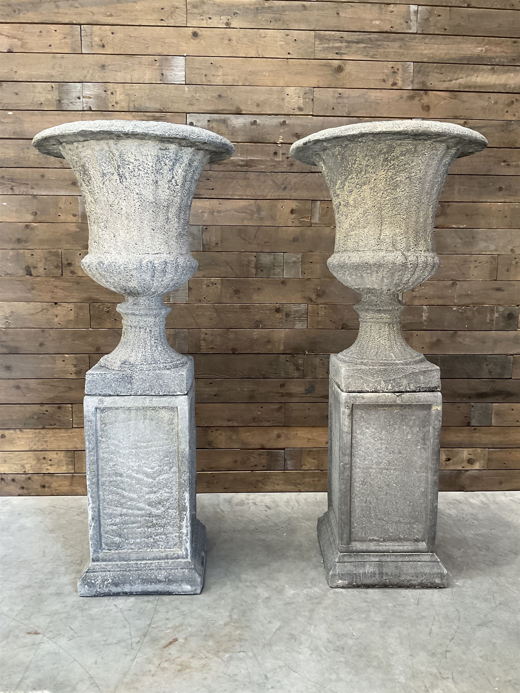 Pair of large Georgian design cast stone garden urns, egg and dart border, tapering column on square base, raised on square column