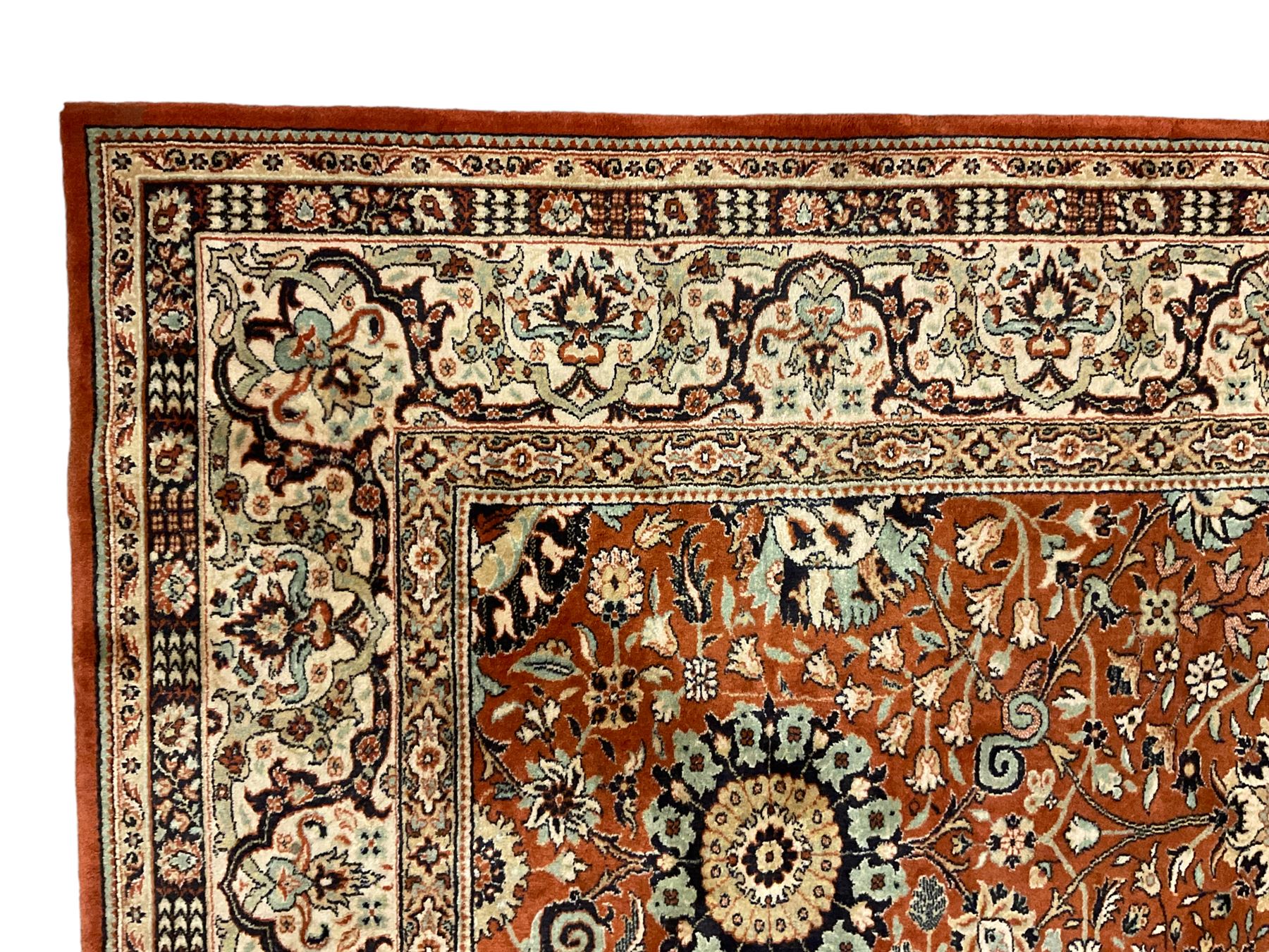 Persian design carpet, rust ground field decorated with large stylised plant motifs surrounded by smaller floral motifs, repeating trailing border