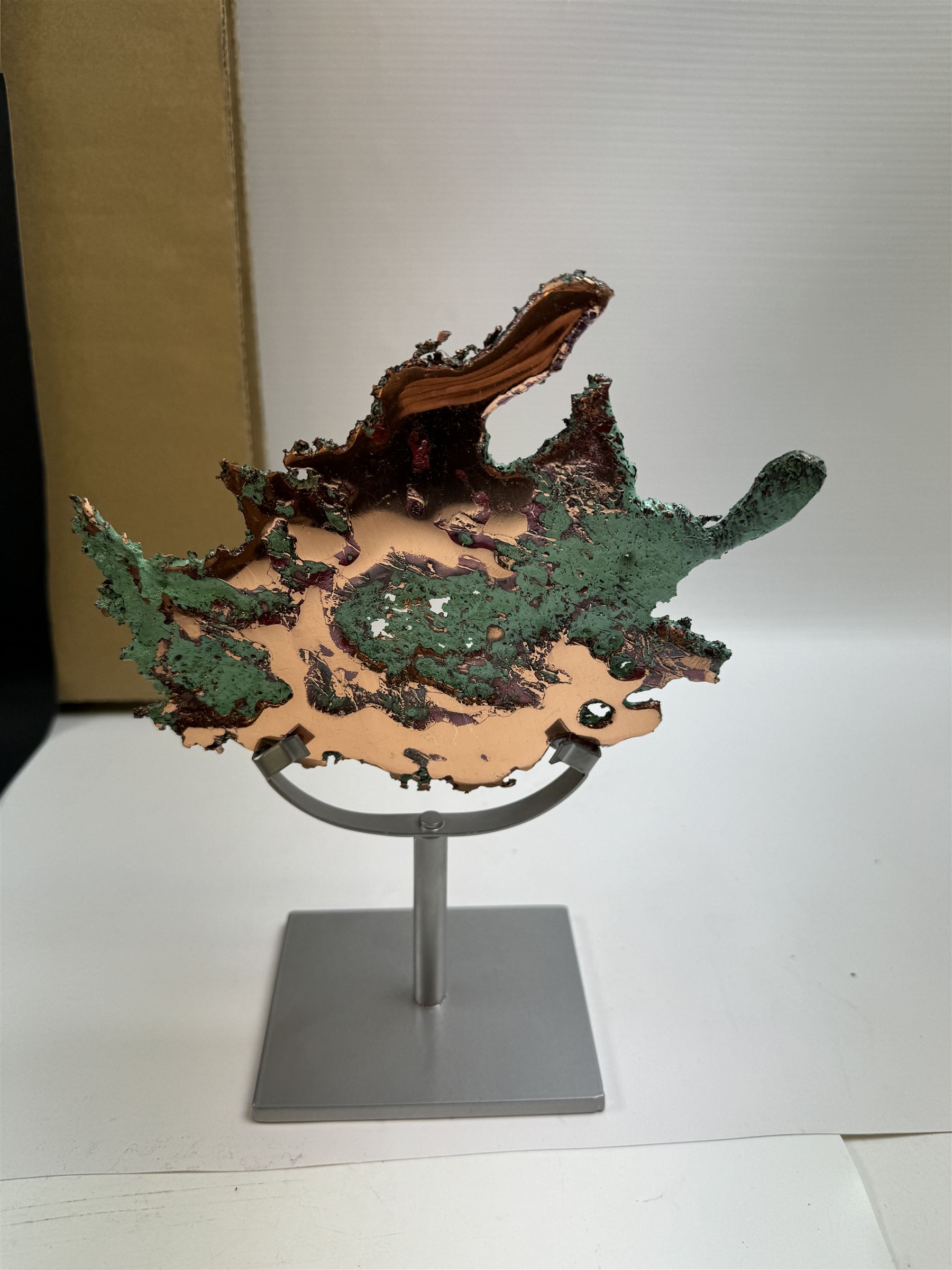 Free form copper splash, with green patina and polished copper accents, upon a silver metal stand, H20cm 