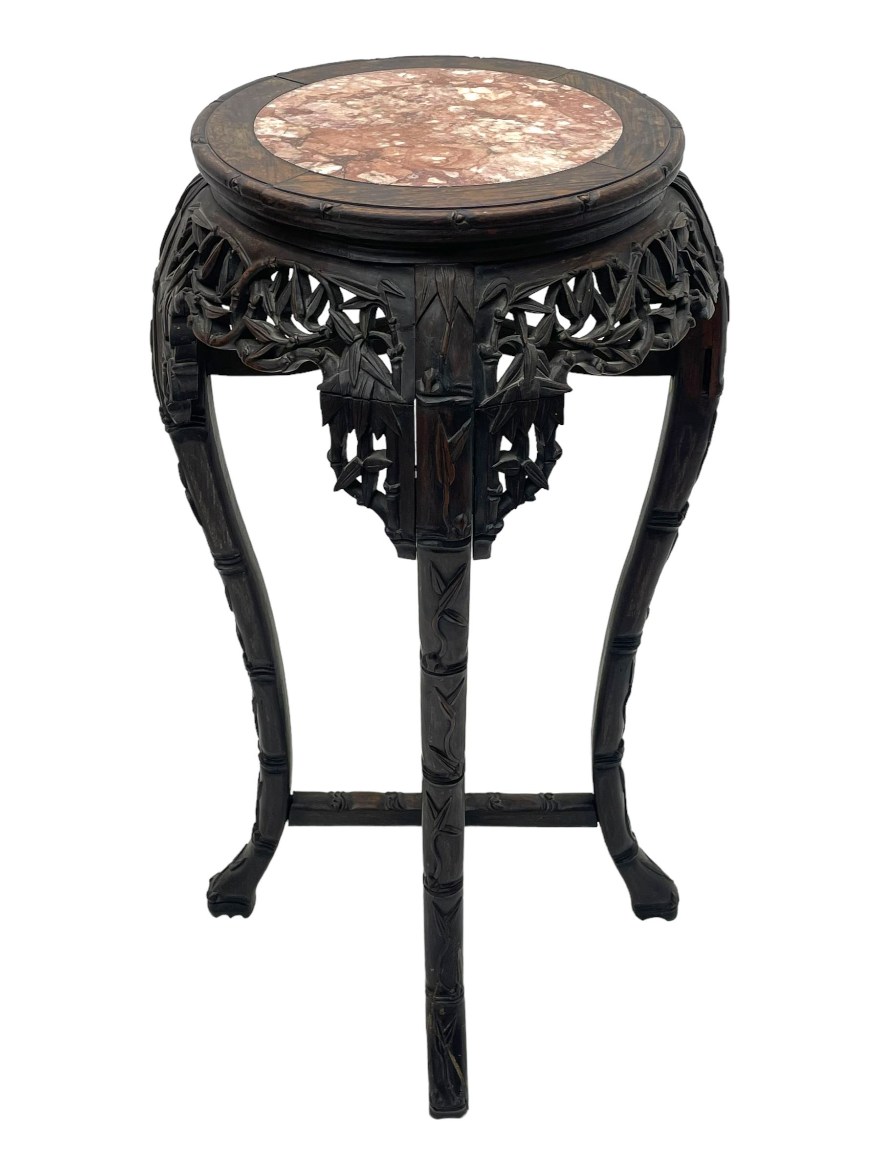 Early 20th century Chinese hardwood plant stand, circular top with marble inset, carved and pierced with interlacing foliage, on leaf carved supports united by x-framed stretchers