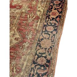 Persian Heriz design rug with red ground, the field featuring a central medallion with floral and geometric motifs, surrounded by ivory spandrels, the main border showcasing a series of floral patterns on a dark blue ground