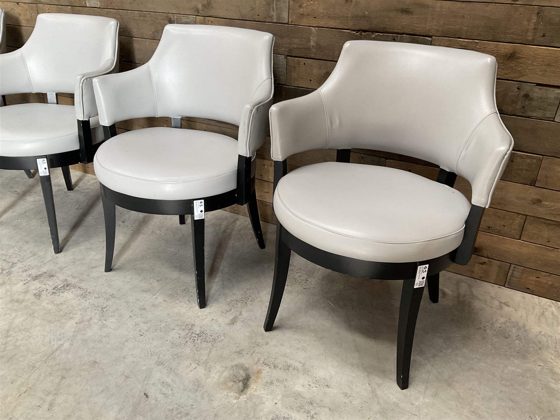 Four ebonised framed tub shaped armchairs, upholstered in grey fabric