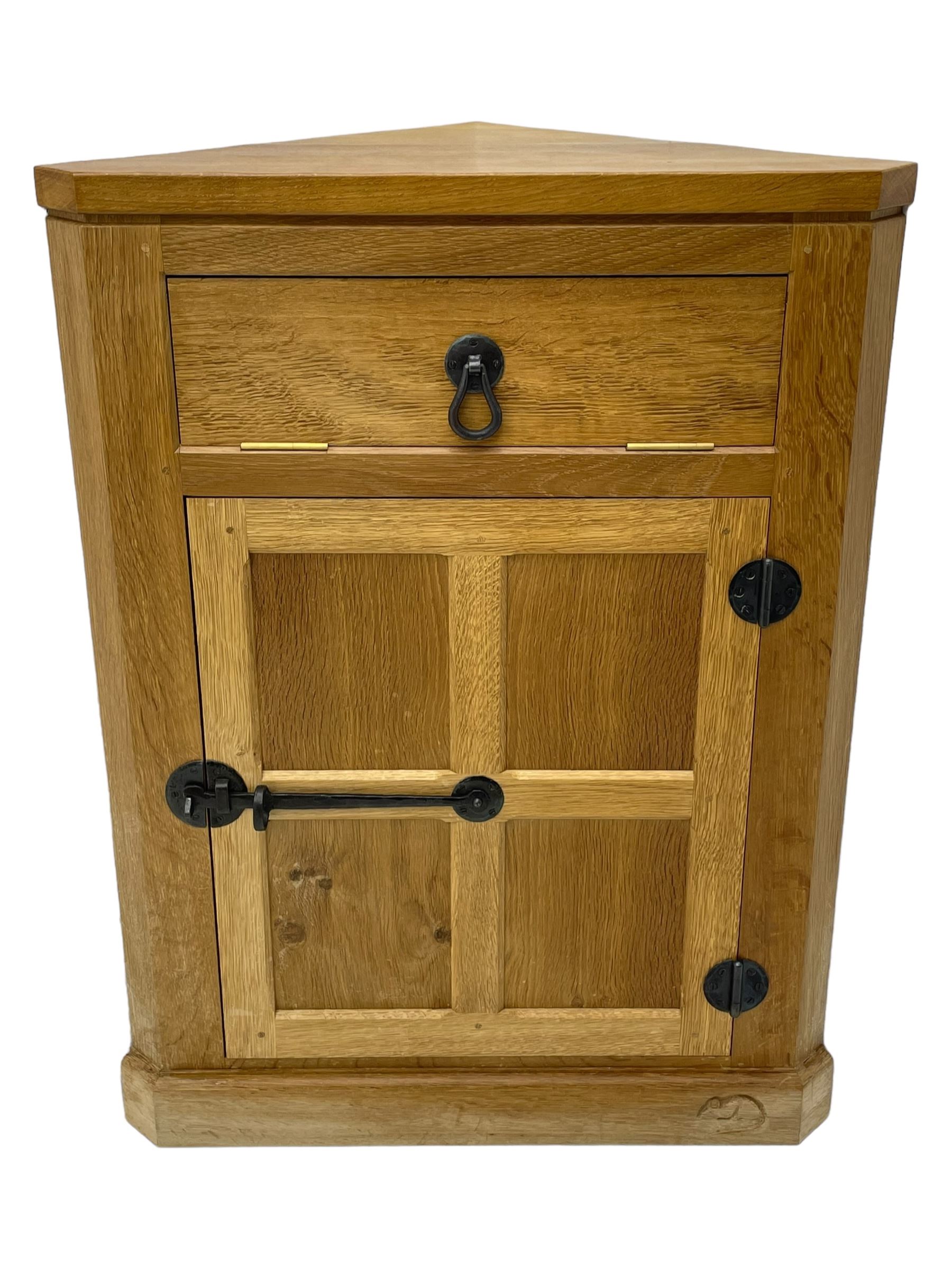 Mouseman - oak floor standing corner cupboard, fall front compartment over single panelled door, with wrought metal loop handle and latch, on moulded plinth base, carved in relief with mouse signature, by the workshop of Robert Thompson, Kilburn 