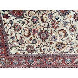 Persian Sarough ivory ground rug, the field decorated with curled leafy branches and palmettes, crimson ground border decorated with further palmettes and floral sprays, within guard stripes 