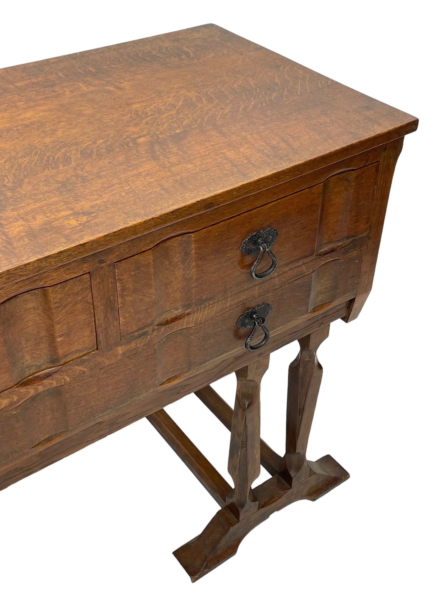 Arts & Crafts design oak chest on stand, rectangular top over two short and one long drawer, on a series of shaped and tapered supports with carved and beaded decoration, united by chamfered stretchers rails, on sledge feet 