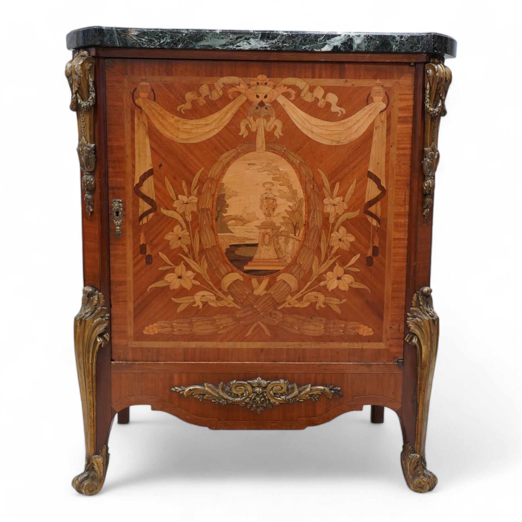 20th century French Kingwood and gilt metal mounted side cabinet, moulded green variegated marble top over single cupboard, enclosed by marquetry inlaid single door, the oval panel depicting urn and bridge in garden landscape, surrounded by fruiting laurel wreath and enclosed by draped linen swags, decorated with trailing leafy branches and flower heads, canted corners with scroll and acanthus leaf cast mounts decorated with laurel swags, curled acanthus leaf lower mounts terminating to scrolled terminal caps, the interior fitted with single shelf 