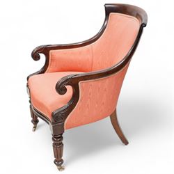 Regency mahogany library reading chair, curved and rolled cresting rail with scroll carved ears, upholstered in pink fabric with sprung seat, out swept arms with scroll carved terminals, on turned and lobe carved front supports with brass and ceramic castors 