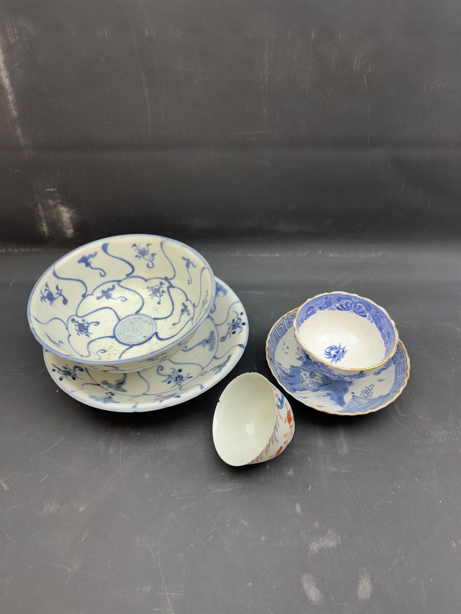 Early 19th century Chinese Tek Sing bowl, decorated with stylised blossoms, with 'Nagel Auctions' label to base, H6.5cm D15.5cm, together with a  Tek Sing similar saucer, D18cm, a Chinese tea bowl decorated in blue and red blossoming flowers, a Chinese blue and white saucer, and an English blue and white Willow pattern tea bowl, (5)