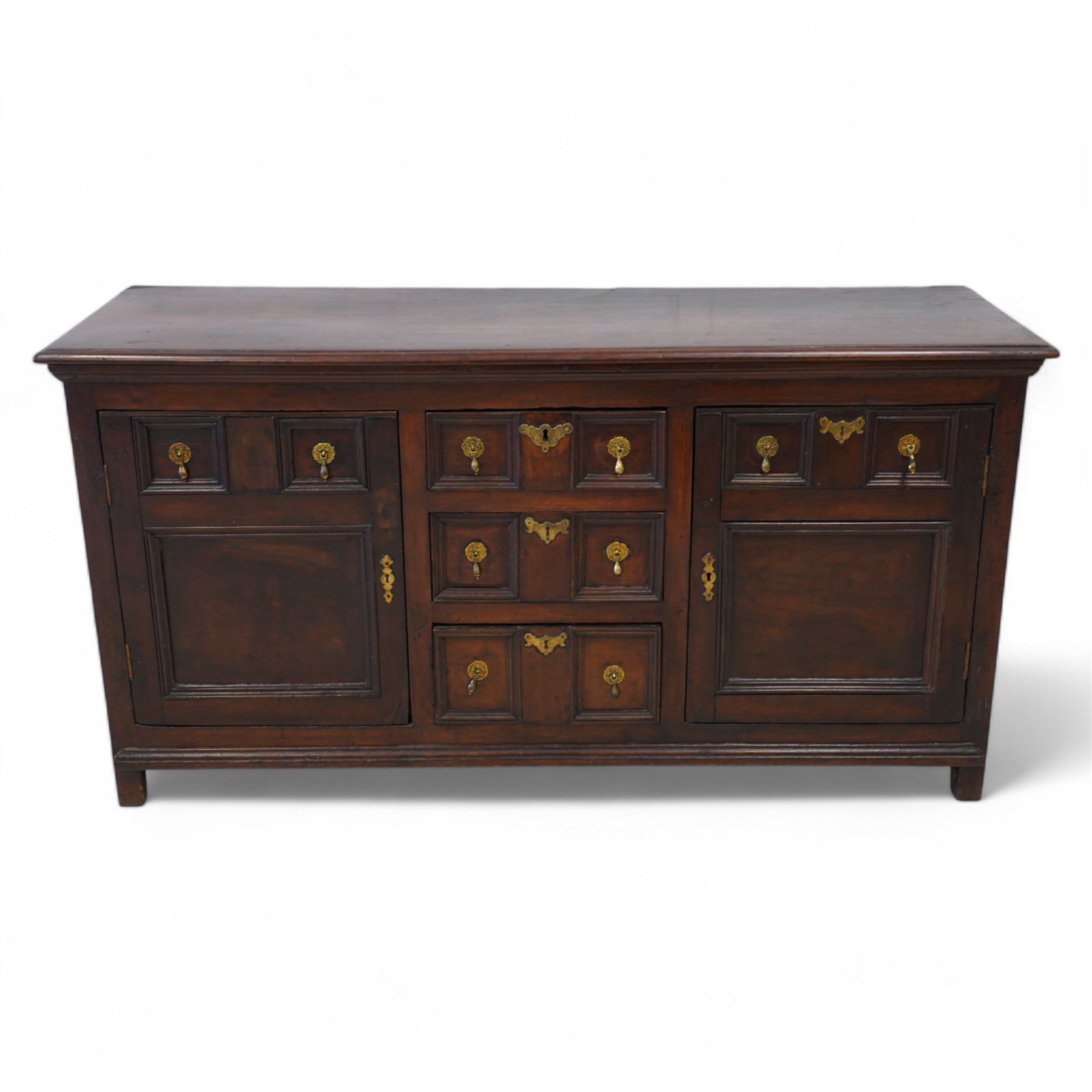 George III elm dresser base, the rectangular top with moulded edge, fitted with three central graduating twin-panelled drawers, flanked by two cupboard doors moulded with false drawer facias over large panels, lower moulded edge over stile feet