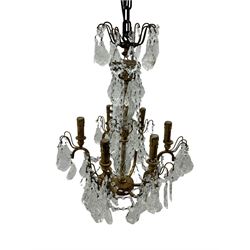 India Jane Interiors - brass and crystal six-branch chandelier, each branch holds a single candle-style bulb holder detailed with scrolling design, the chandelier is adorned with numerous crystal pendants and octagonal beads, which hang from each arm and from the cut crystal central column