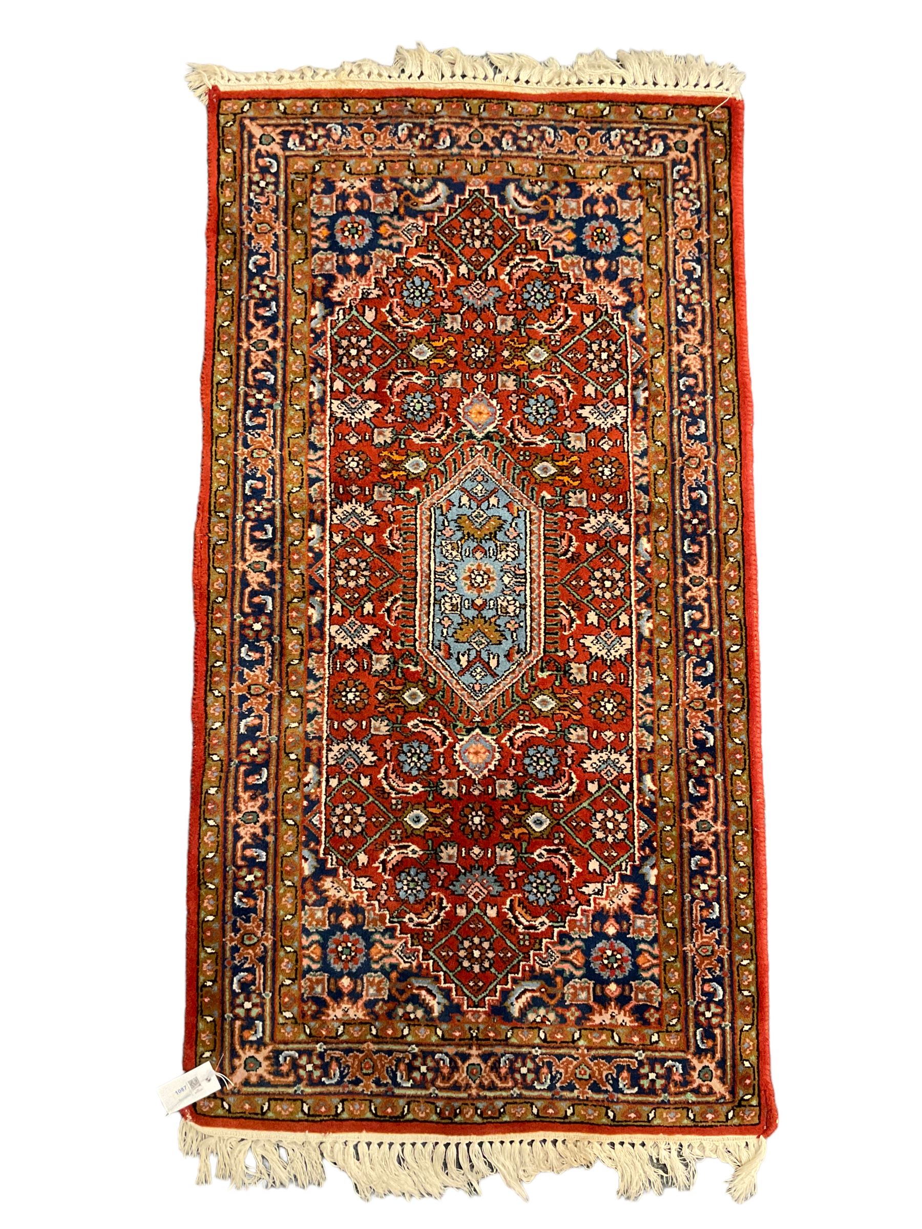 Small crimson ground rug, the extending lozenge field decorated with Herati motifs and flower heads, repeating guarded border