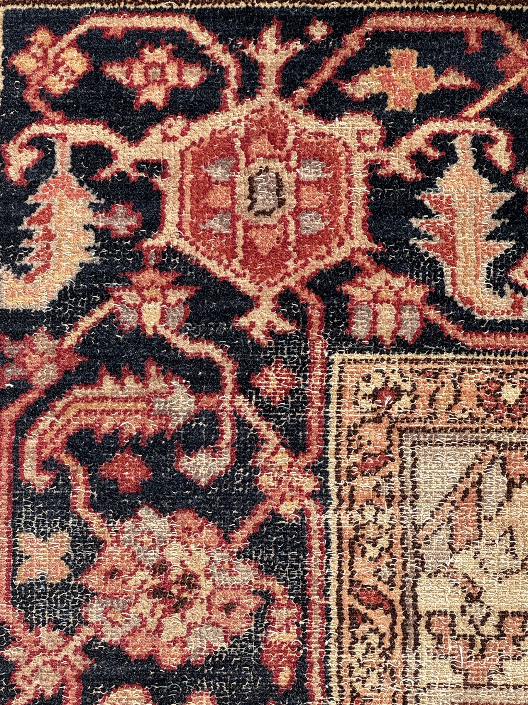 Persian Heriz design rug with red ground, the field featuring a central medallion with floral and geometric motifs, surrounded by ivory spandrels, the main border showcasing a series of floral patterns on a dark blue ground