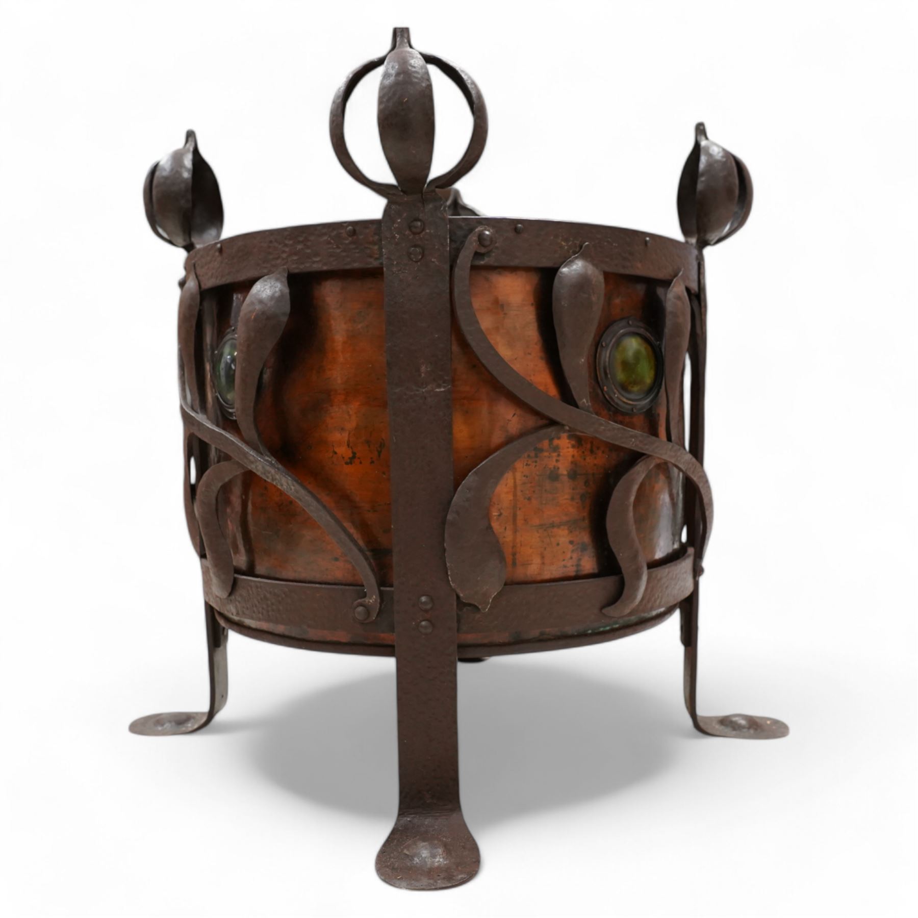 Late 19th to early 20th century Arts & Crafts wrought metal and copper coal or log basket, hammered metal frame, on four supports with bulbous onion finials terminating to pad feet, the frame decorated and united by curled stylised leaf pattern, the copper inner decorated with cabochons mounts, fitted with metal liner 