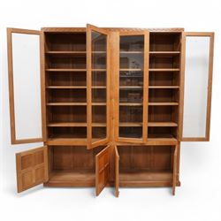 Eagleman - oak bookcase, penny moulded cresting rail over four glazed doors and four panelled doors, fitted with adjustable shelves, on moulded plinth base, panelled sides, carved with eagle signature, by Albert Jeffray, Sessay, Thirsk