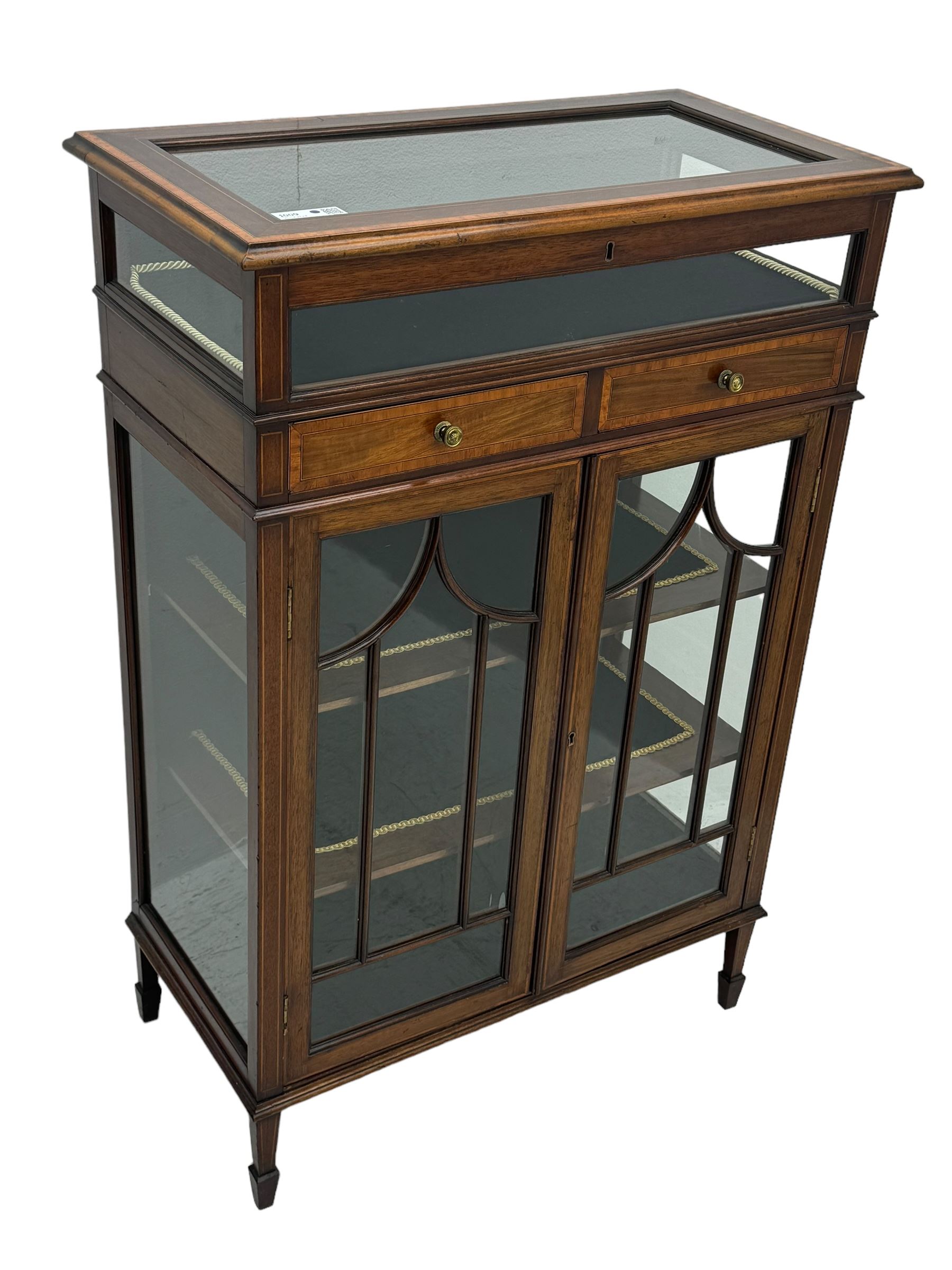 Edwardian mahogany bijouterie display cabinet, featuring satinwood inlay and crossbanding, hinged glazed top fitted with two banded drawers, over two astragal glazed doors enclosing black wool baize lined shelves with gold trim, supported by spade feet