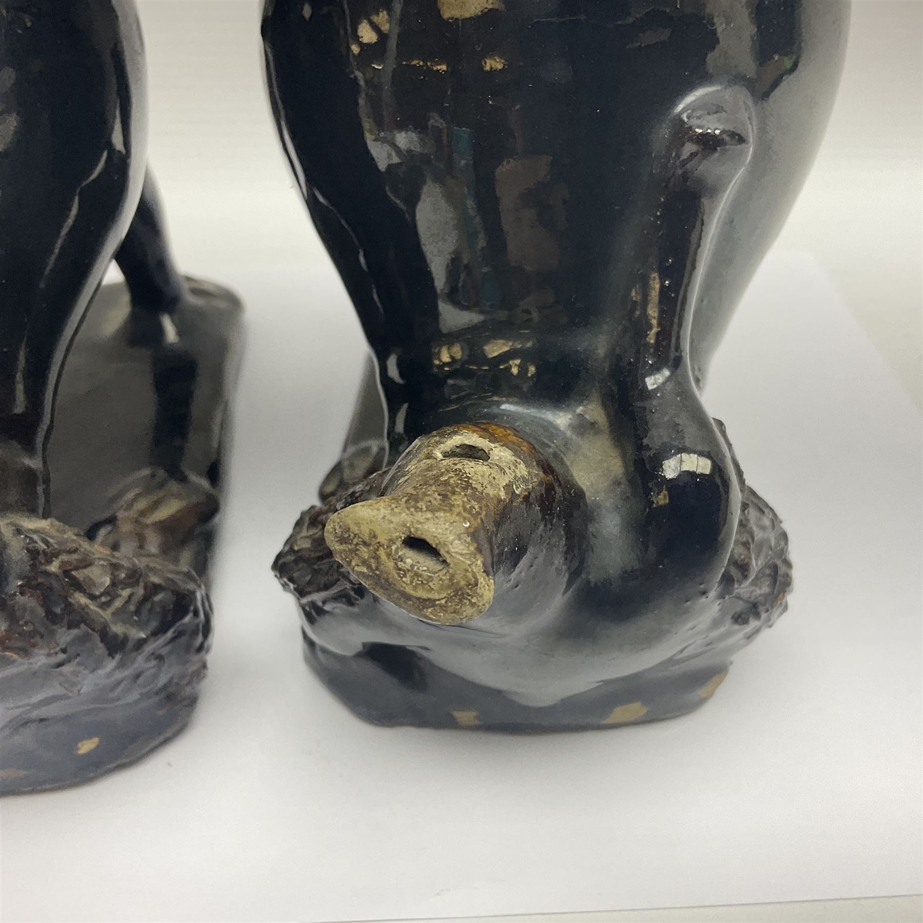 Pair of unusual early English pottery figures, modelled in the form of seated dogs with baskets between their jaws, the tails forming whistles, each upon rectangular base, overall H22cm