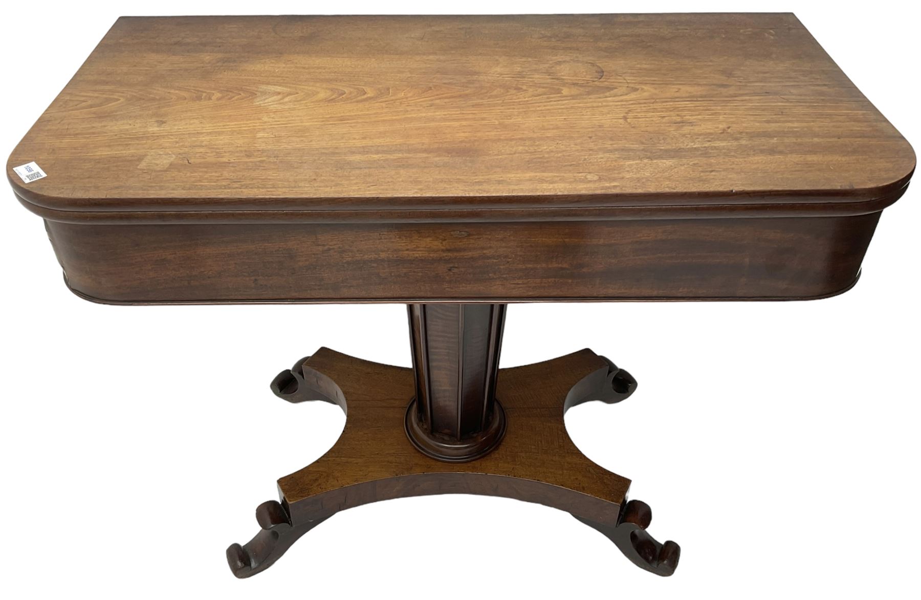 William IV mahogany tea table, rectangular fold-over top over banded frieze, tapering pedestal base with moulded vertical rails, on quadruform base with C-scroll feet