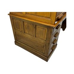 Early 20th century oak tambour roll-top desk, the top with fitted interior including drawers, pigeonholes and compartments, the twin pedestals fitted with four drawers with carved handles, supported by plinth base 