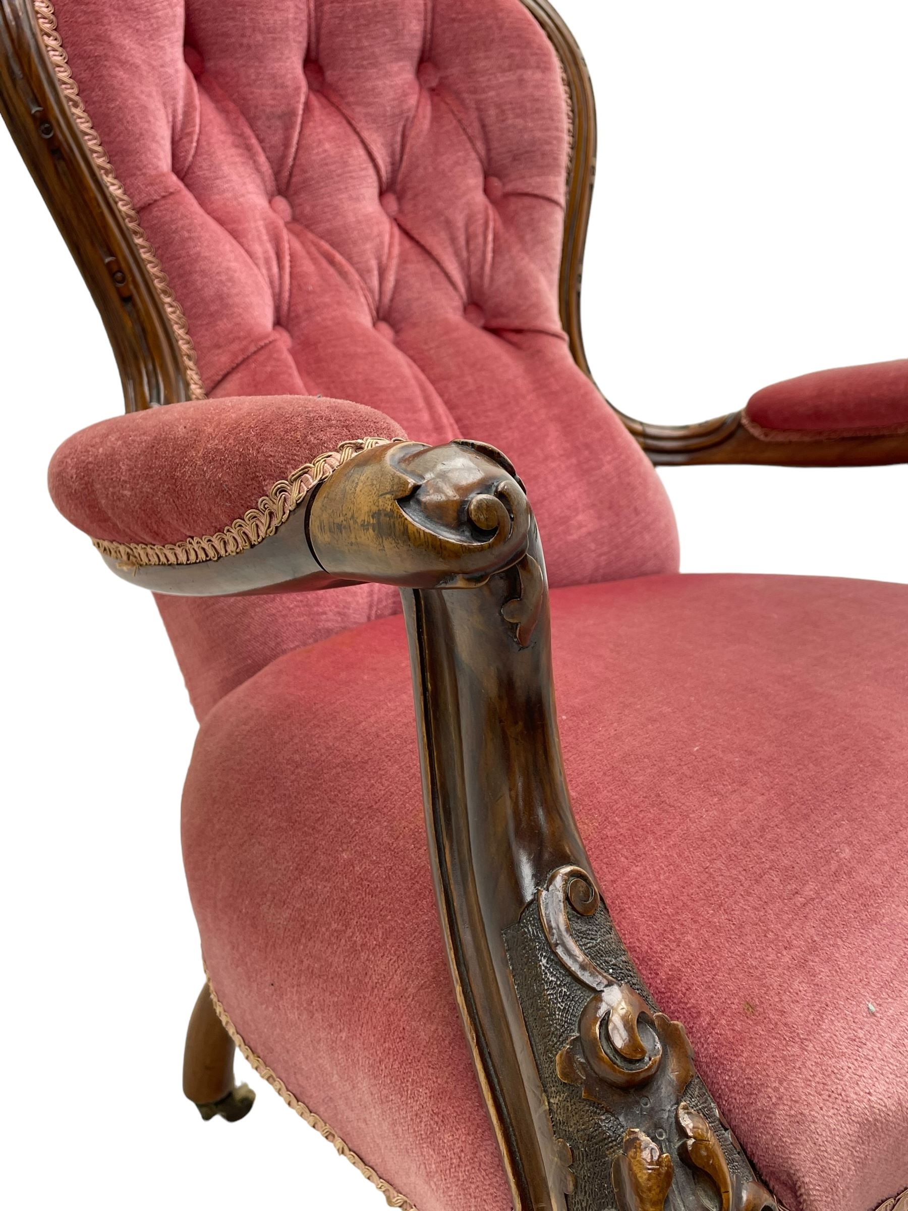 Victorian carved walnut open armchair, foliate carved cresting rail over butted back and sprung seat, upholstered in pink velvet scrolled arm terminals with moulded scrolling vines terminating to cabriole supports and ceramic castors