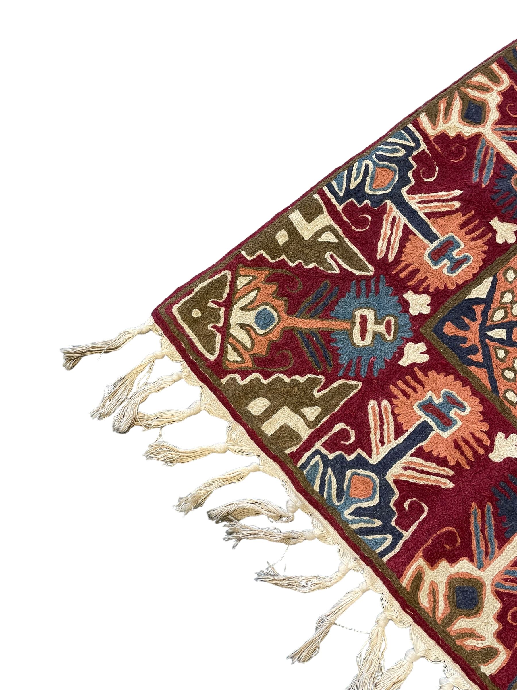 Caucasian design crewelwork hanging, crimson ground, the field decorated with geometric designs, the wide guard band with repeating stylised plant  motifs