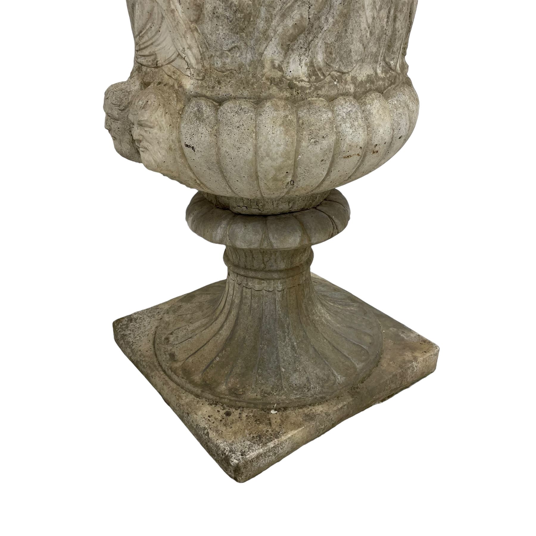 Cast stone Campana shaped urn, decorated with festival scenes over gadrooned underbelly, circular foot on square base