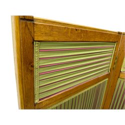 Edwardian oak and fabric folding screen, featuring three panels with oak frames, one side covered in green striped fabric with decorative trim, the reverse side in pink moiré effect fabric, connected by brass hinges