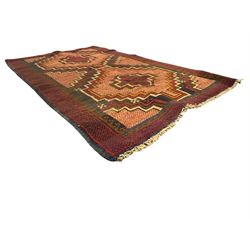 Baluchi crimson ground rug, the central field decorated with two stacked geometric lozenge medallions, surrounded by stepped multicoloured motifs, the wide border with alternating angular motifs in deep red, within a narrow brown guard stripe