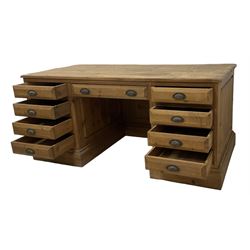 20th century waxed pine kneehole desk, rectangular top over nine drawers with cup handles, on moulded plinth base