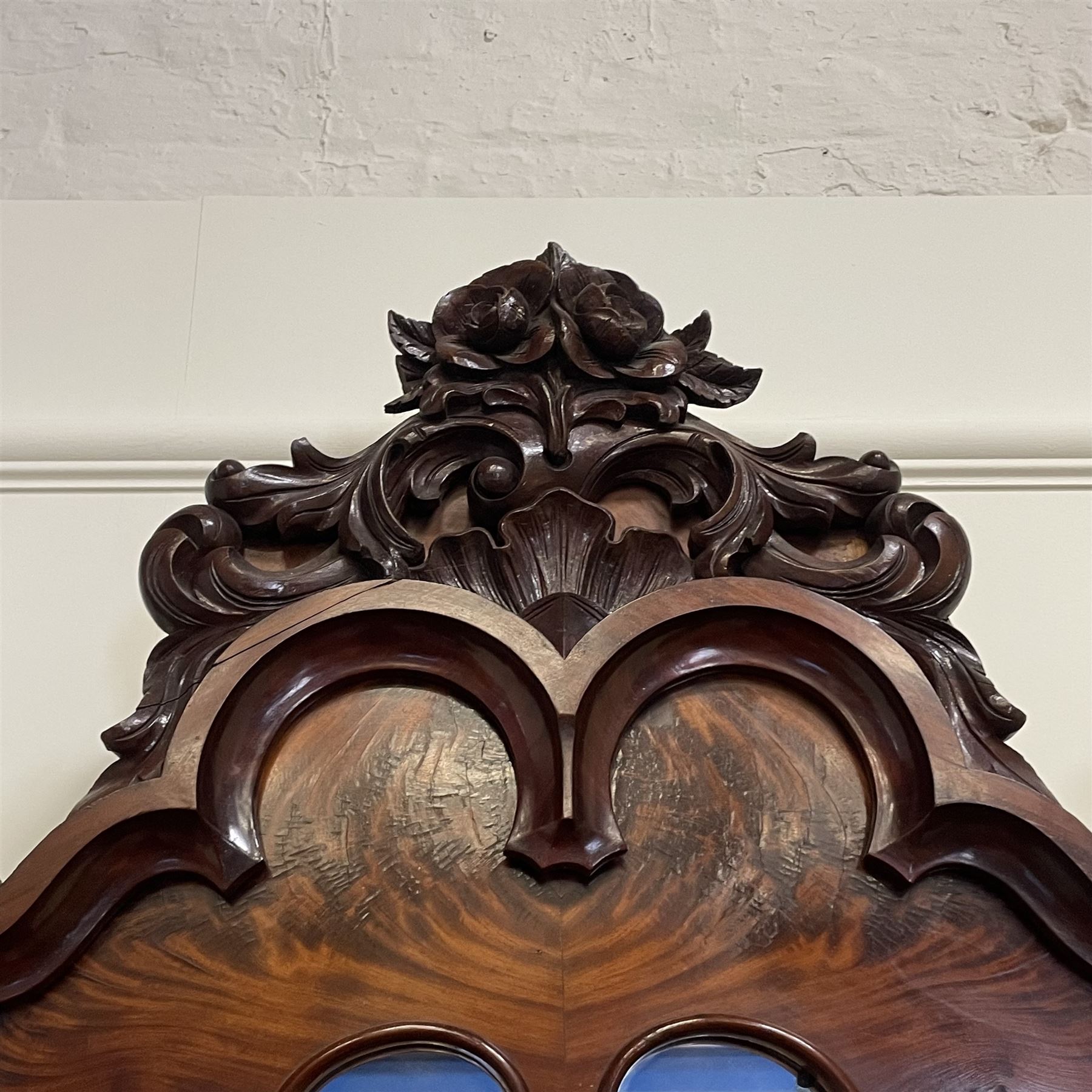 Tall Victorian figured mahogany twin pedestal dressing table, the tall mirror with flower head and scrolled leaf carved pediment, flanked by two turned and carved finials over faceted lancet arched lantern tops, plane mirror plate enclosed by shaped frame, pierced and undulating moulded uprights, on C-scroll and curled leaf carved supports fitted with cast brass hinged candle sconces, each pedestal fitted with two small trinket drawers over larger drawer and panelled cupboard, canted corners with matched upright mounts, the cupboard doors enclosing slides, on scroll carved feet 