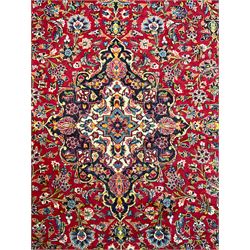 Persian Kashan crimson ground carpet, floral design central medallion surrounded by trailing leafy branches and stylised plant motifs, multi-band border with repeating floral design