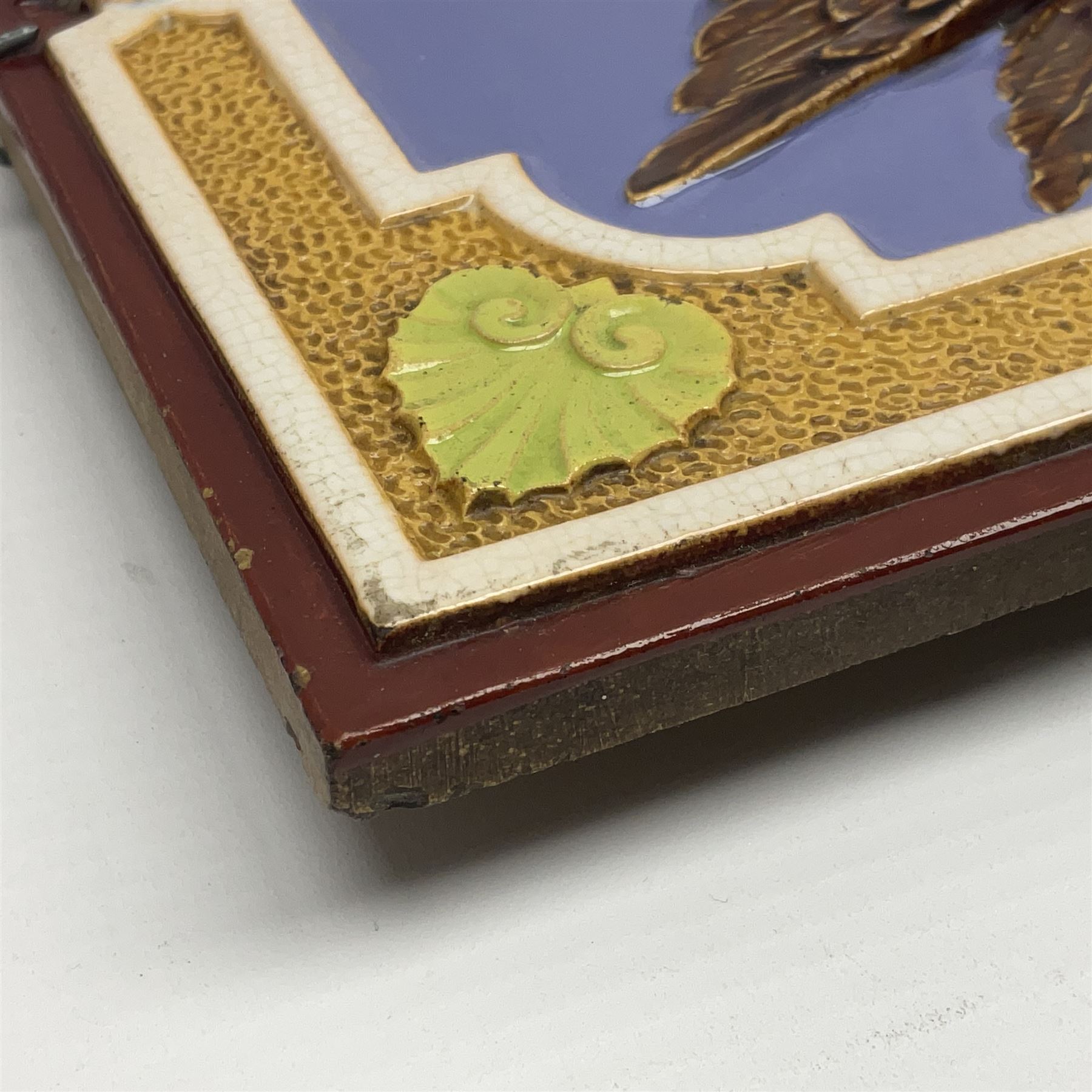 19th century Minton & Co majolica tile, decorated in relief with a bird upon a fruiting branch against a blue ground, with textured ochre border and anthemion to each corner, impressed mark verso, H19.7cm