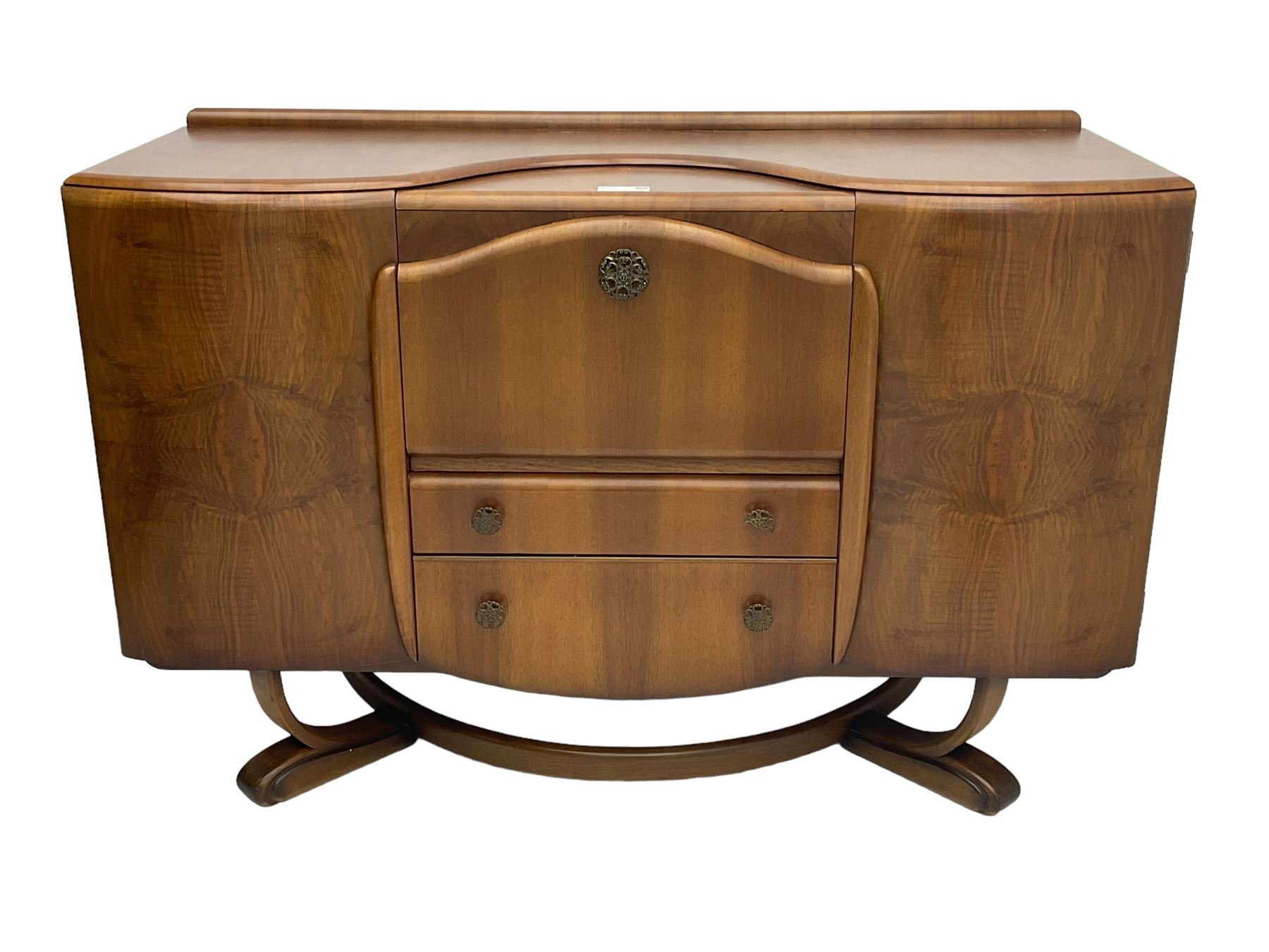 Beautility - mid-20th century walnut sideboard, fall-front with sliding top enclosing mirror interior, fitted with two drawers and flanking cupboards, on sledge feet with curved stretchers 