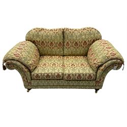 Traditional design two seat sofa, high back with scrolled arms, upholstered in beige fabric with red and green damask motifs, on castor supports (L178cm, D100cm, H89cm); matching armchair (L109cm, D89cm, H89cm)