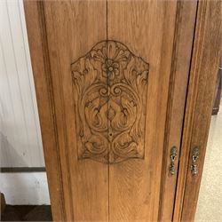 Late 19th century oak triple wardrobe, wide central bevelled mirror door, flanked by two panelled doors each carved with scrolling leaves and flower heads, on moulded skirt base 