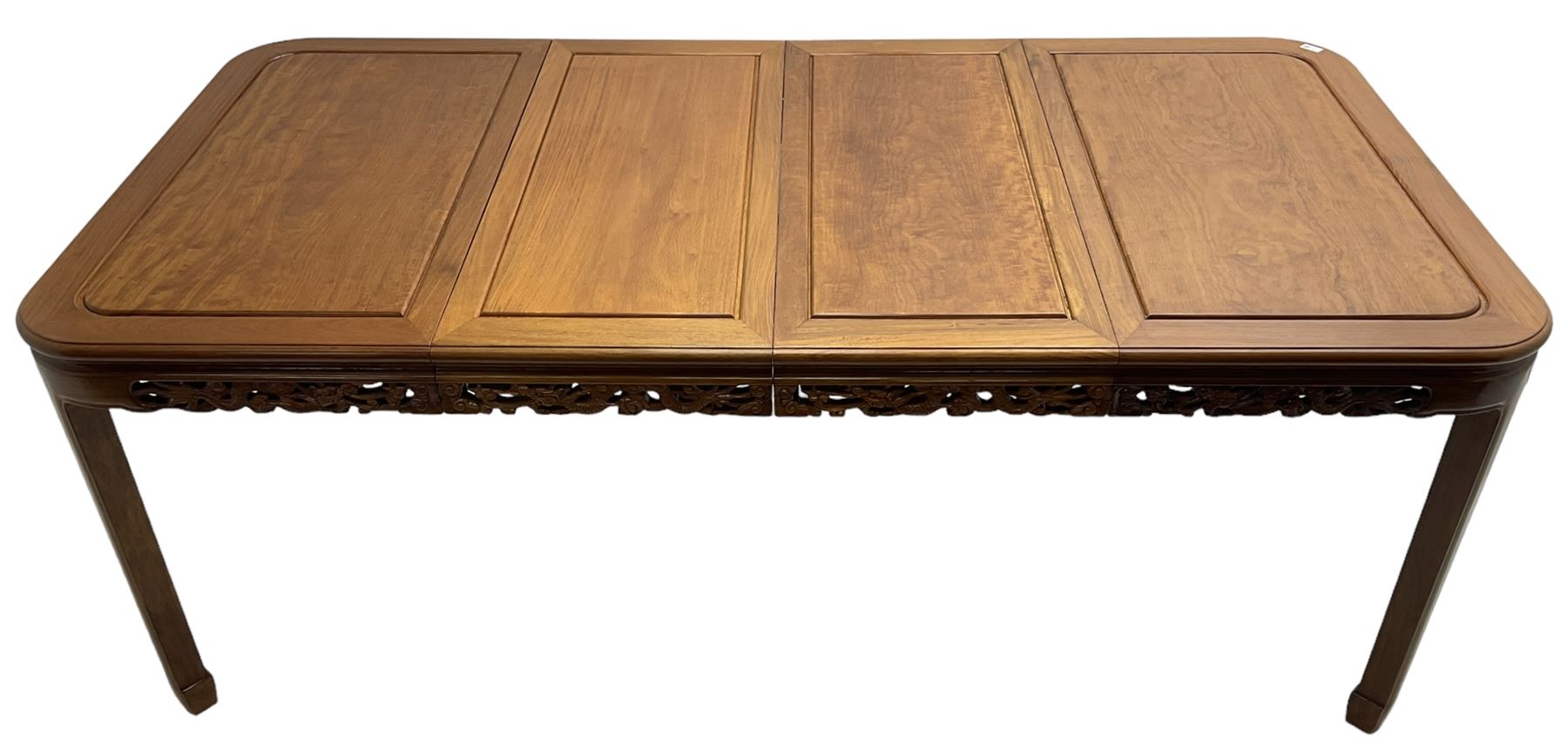 Late 20th century Chinese carved hardwood extending dining table, rectangular panelled top with rounded corners over a pierced frieze carved with dragon motifs and scrolling foliate decoration, with two additional leaves