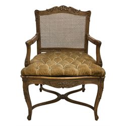 Late 19th century French carved beech open elbow chair, shaped cresting rail carved with central shell and curl leafage, cane work seat and back with buttoned loose seat cushion, the open arms carved with scrolled terminals and acanthus leaves, on cabriole supports with carved decorated united by shaped and moulded x-framed stretchers 