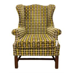 Georgian design mahogany framed wingback armchair, upholstered in spotted fabric in shades of grey and green, on moulded square supports united by stretchers 