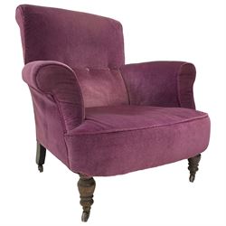 Late Victorian upholstered armchair, in deep purple velvet fabric, buttoned backrest, rolled arms, on splayed back and turned front supports with castors