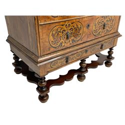 18th century inlaid walnut chest on stand, ovolo-moulded rectangular top inlaid with ebony panels each decorated with scrolling foliage, flower heads and birds, fitted with two short over three long drawers, the drawer fronts decorated with ebony panels enclosing curled leaf inlays, the base fitted with single drawer on turned supports united by waved stretchers, on turned bun feet 