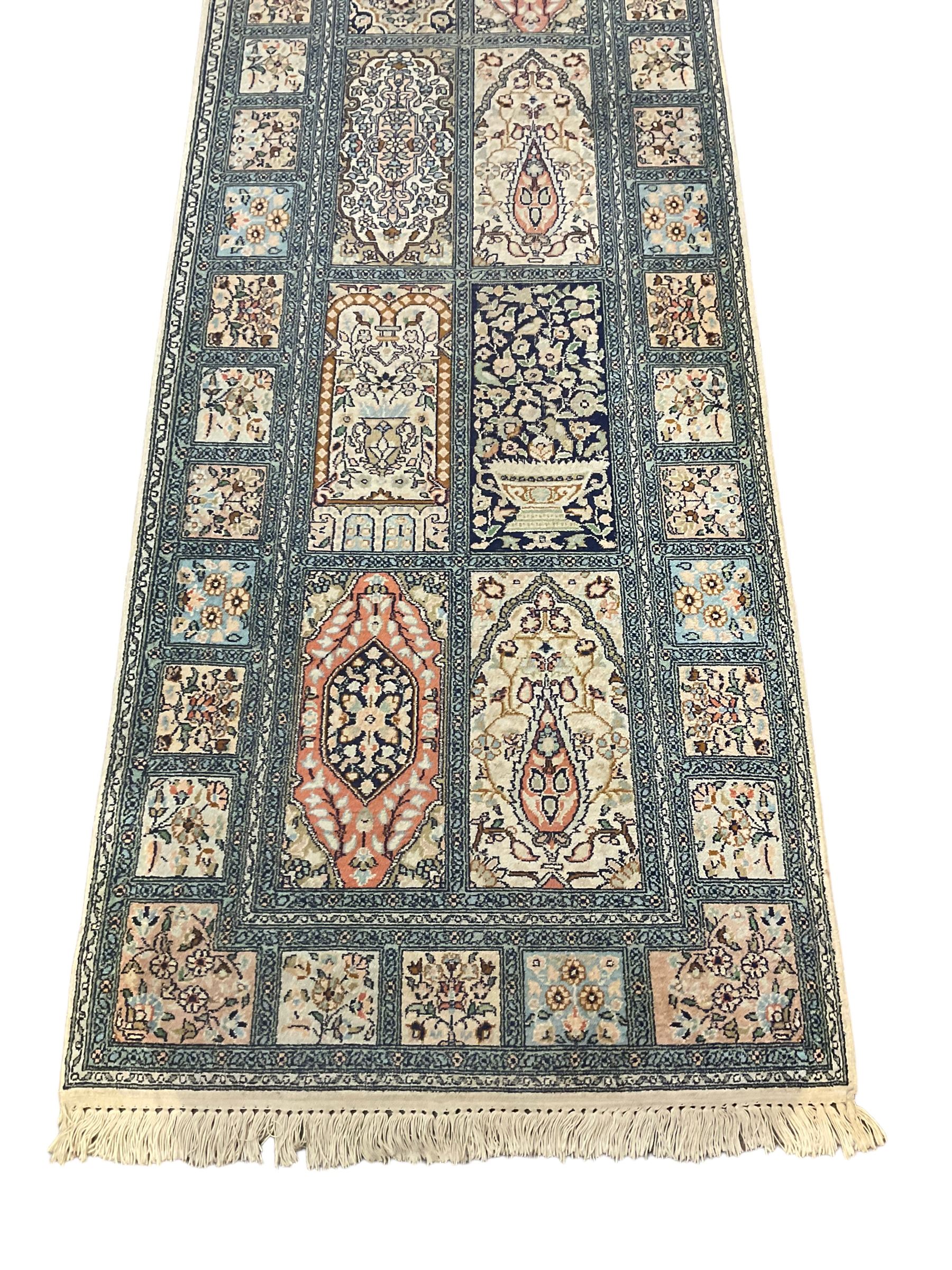 Fine Persian Kashmir ivory and pale indigo ground runner rug, the field decorated with sixteen rectangular panels depicting Mirab motifs and other traditional carpet designs, the border with repeating square panels of floral bouquets and foliate patterns