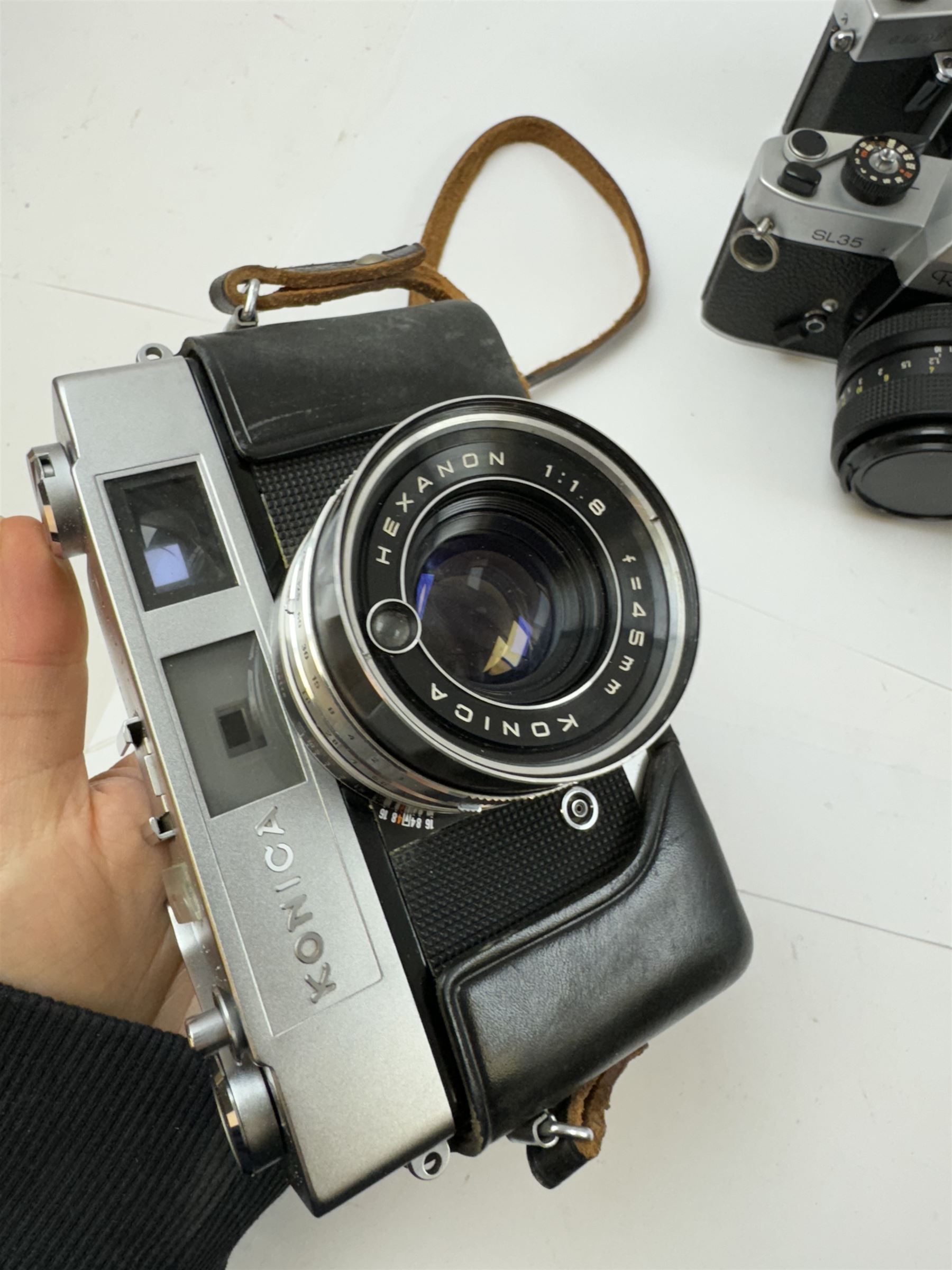 Five SLR cameras, to include Rolleiflex SL35, with a Rollei-HFT Planar 1.8/50 lens serial no. 1246774, Topcon Uni serial no. 5417650, with a Topcor Kogaku UV 1:2 f=53mm lens serial no. 5413035, Bell & Howell Auto35/Reflex Design 237, with a Canon EX 50mm 1:1.8 lens serial no. 92960, Petri GX-1 serial no. 91206945, with a Petri 50mm 1:2.0 lens serial no. 91107428, and a Konica Auto 52 serial no. 1193641, with a Konica Hexanon 1:1.8 f=45mm lens, all in cases 