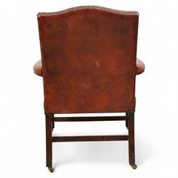 Georgian design Gainsborough elbow chair, upholstered in leather with studwork bands, moulded square supports united by H-stretcher, on brass castors 