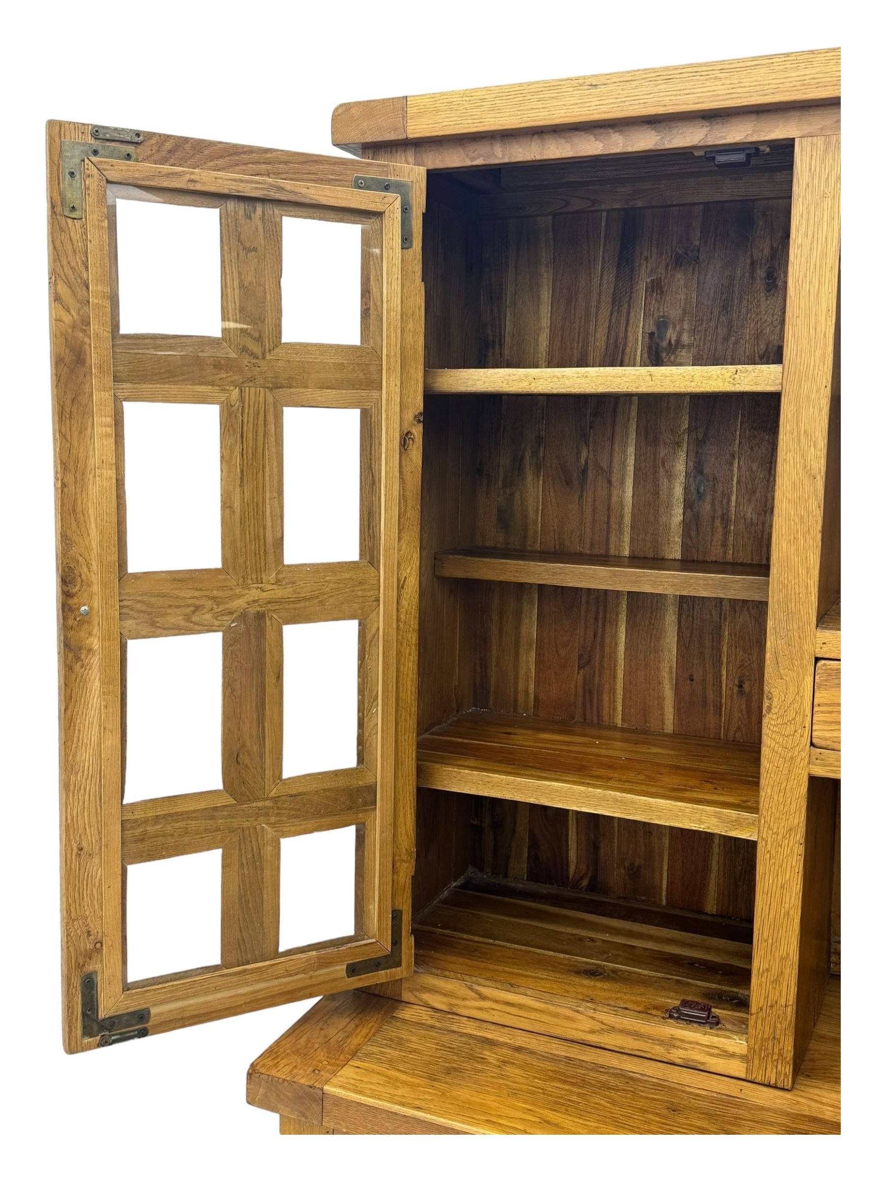 Oak dresser, upper section with twin glazed cupboard doors and central shelving with two trinket drawers, lower section fitted with six drawers over three panelled cupboard doors, raised on shaped feet 