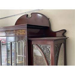 Art Nouveau period inlaid mahogany display cabinet, raised shaped and moulded pediment over projecting moulded cornices, the upper frieze inlaid with trailing branches and tulips, single astragal and bevel glazed door enclosed velvet lined interior fitted with shelves, flanked by curved glass panes decorated with pierced metal foliate spandrels, lower flanking shelves with mirror backs enclosed within shaped and pierced rails inlaid with flower heads, on tapering octagonal supports terminating to compressed pad feet, the lock stamped 'Salmon Bros, London' 